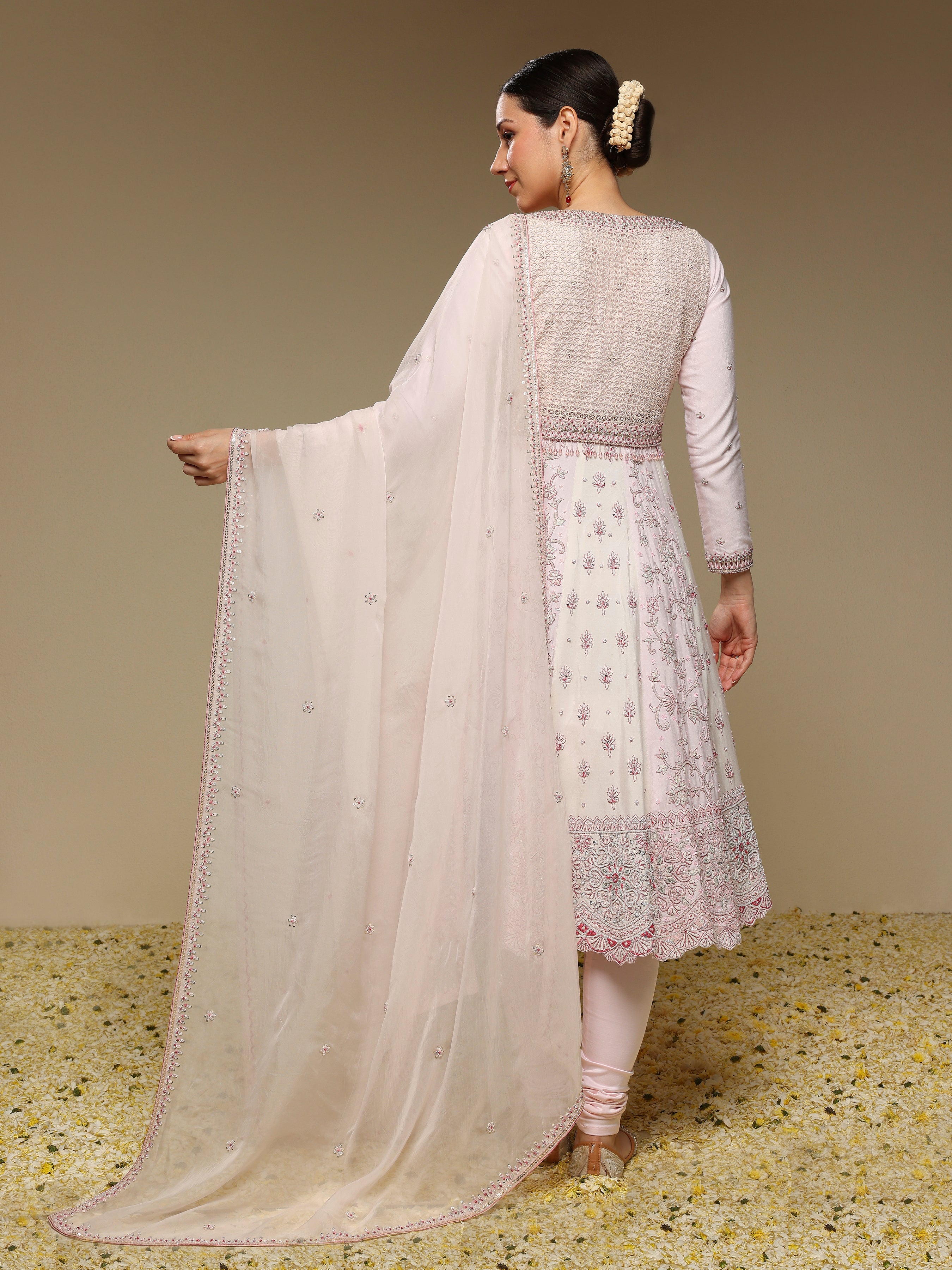 Woman wearing a light pink traditional outfit with a matching dupatta against a neutral background