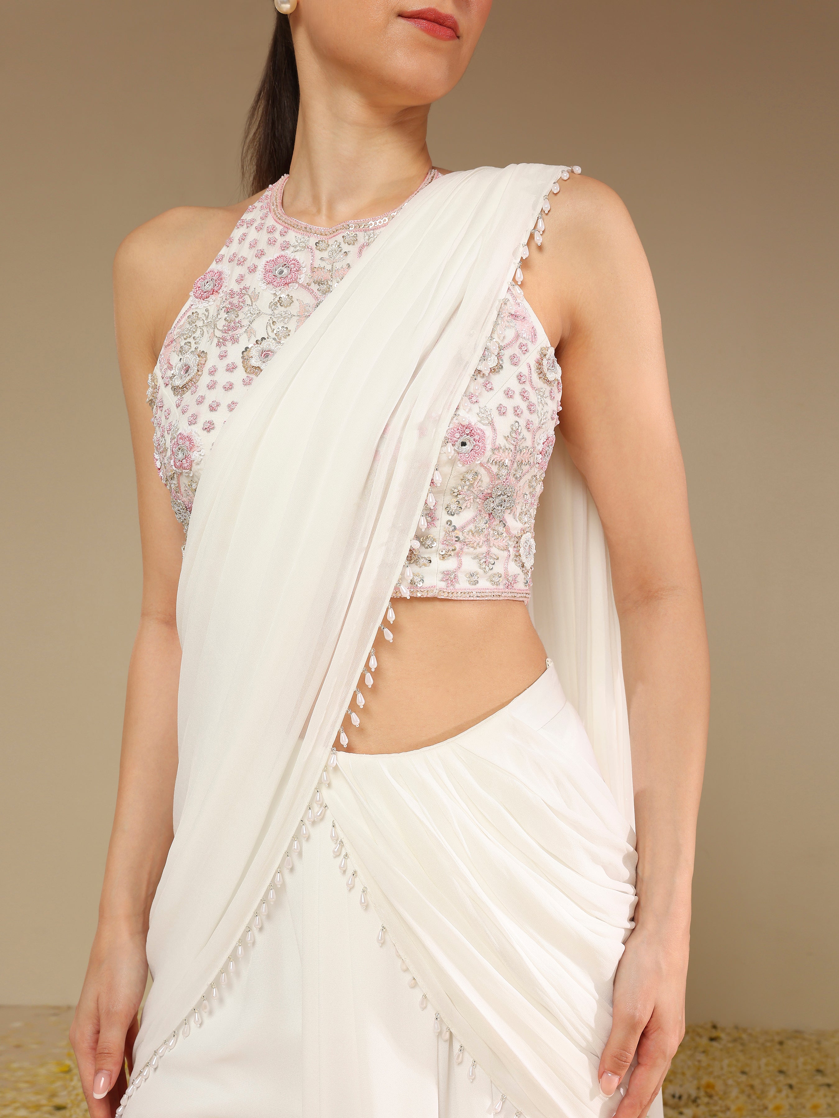 Close-up of zardozi embroidery on blouse and pearl drop detailing on ivory saree pallu