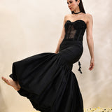 Woman wearing a black evening gown with a textured bodice on a neutral background