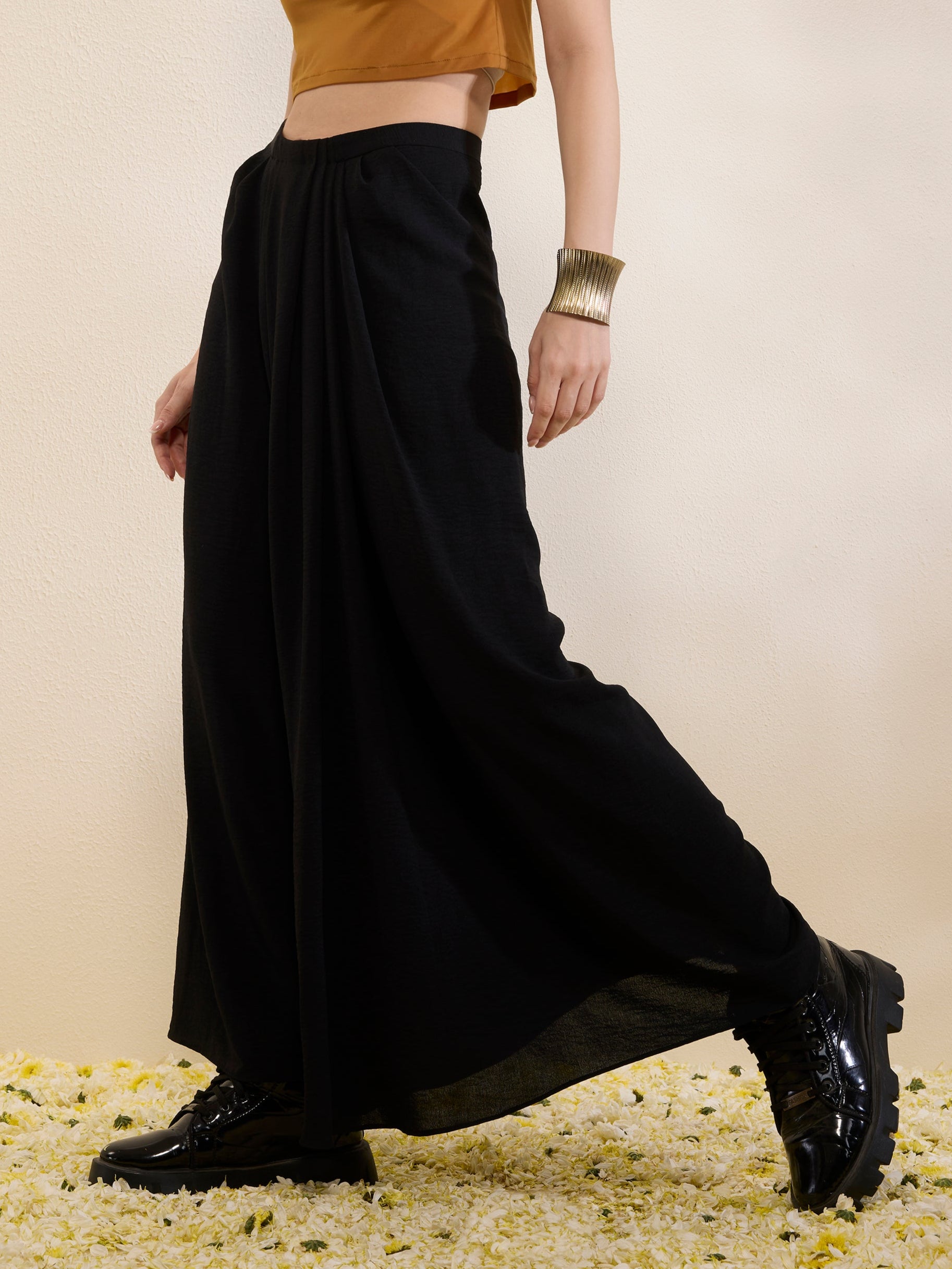 Woman wearing a mustard top and black skirt on a beige background