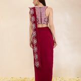 Woman wearing a maroon saree with a matching blouse against a beige background