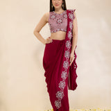 Woman wearing a maroon saree with white floral patterns on a beige background