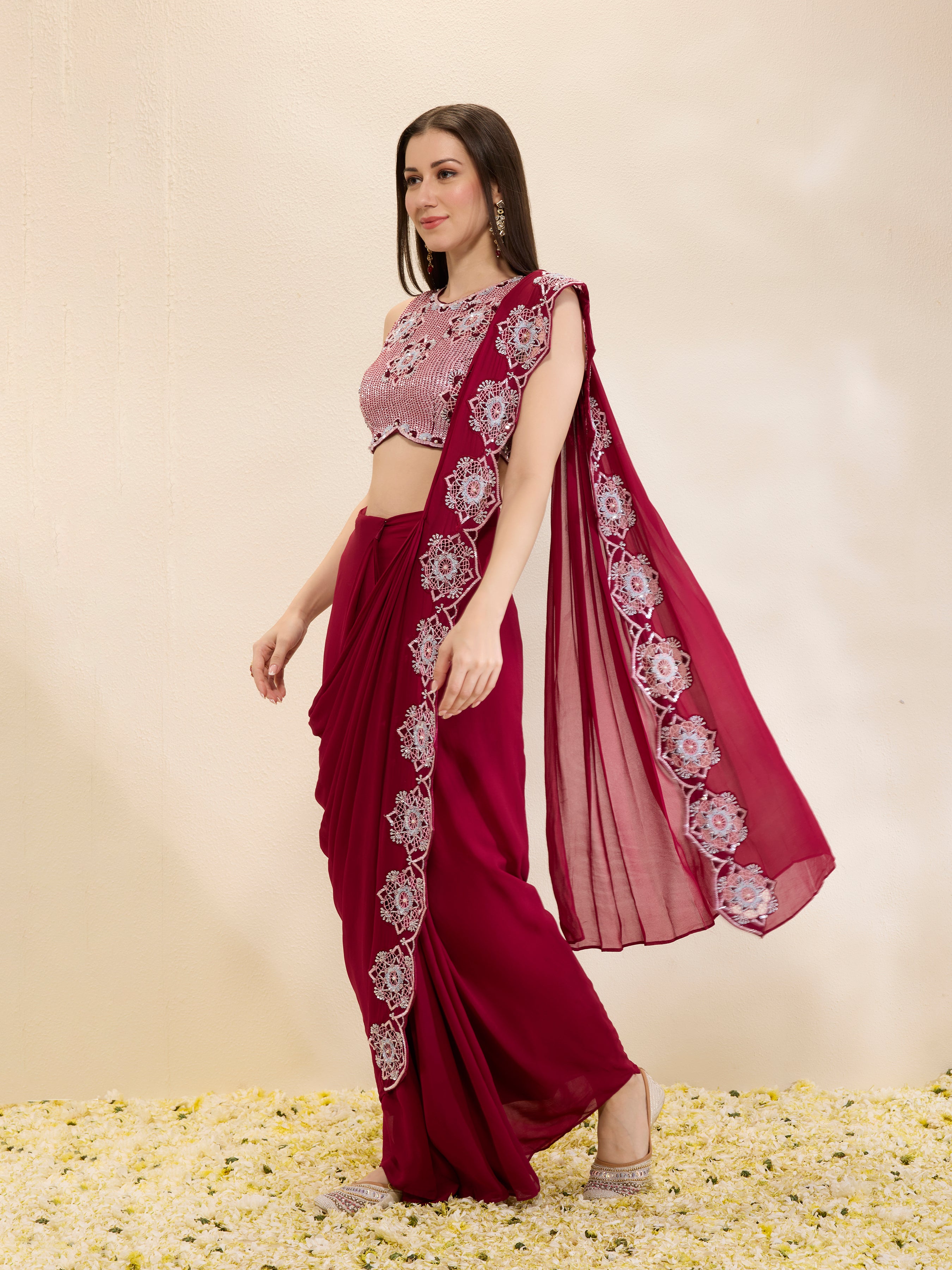 Woman wearing a maroon saree with floral patterns on a beige background