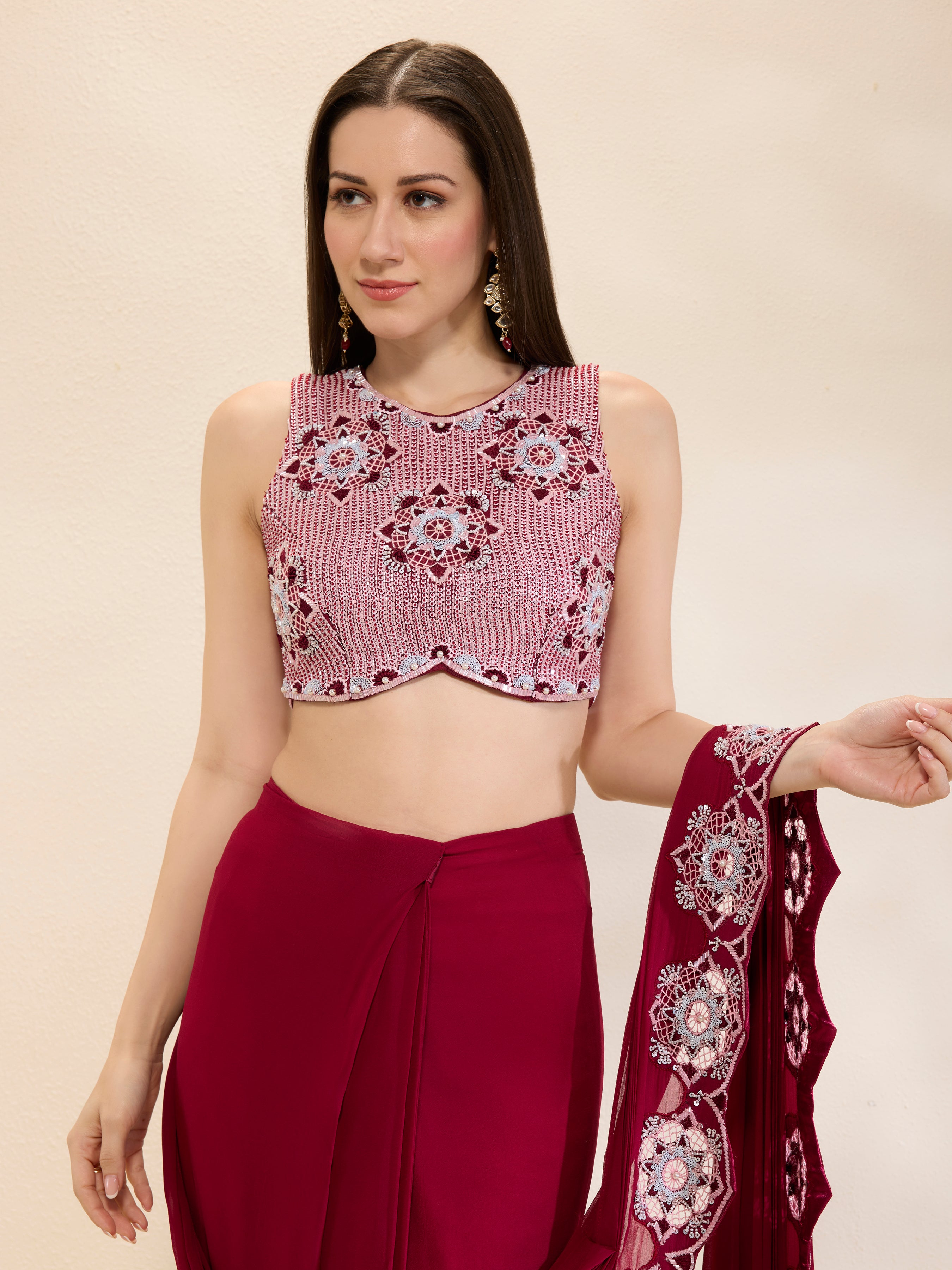 Woman wearing a pink and red traditional outfit with a matching dupatta on a beige background