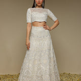 Woman wearing an ivory lehenga outfit showcasing pearl and threadwork embellishments