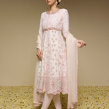 Woman wearing a light pink traditional outfit with a floral pattern on a textured beige background
