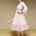 Woman wearing a light pink traditional outfit with floral patterns on a beige background