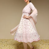 Woman wearing a light pink traditional outfit with floral patterns on a beige background