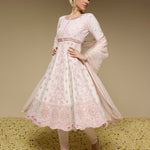 Woman wearing a light pink traditional outfit with floral patterns on a beige background