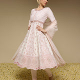 Woman wearing a light pink traditional outfit with floral patterns on a beige background