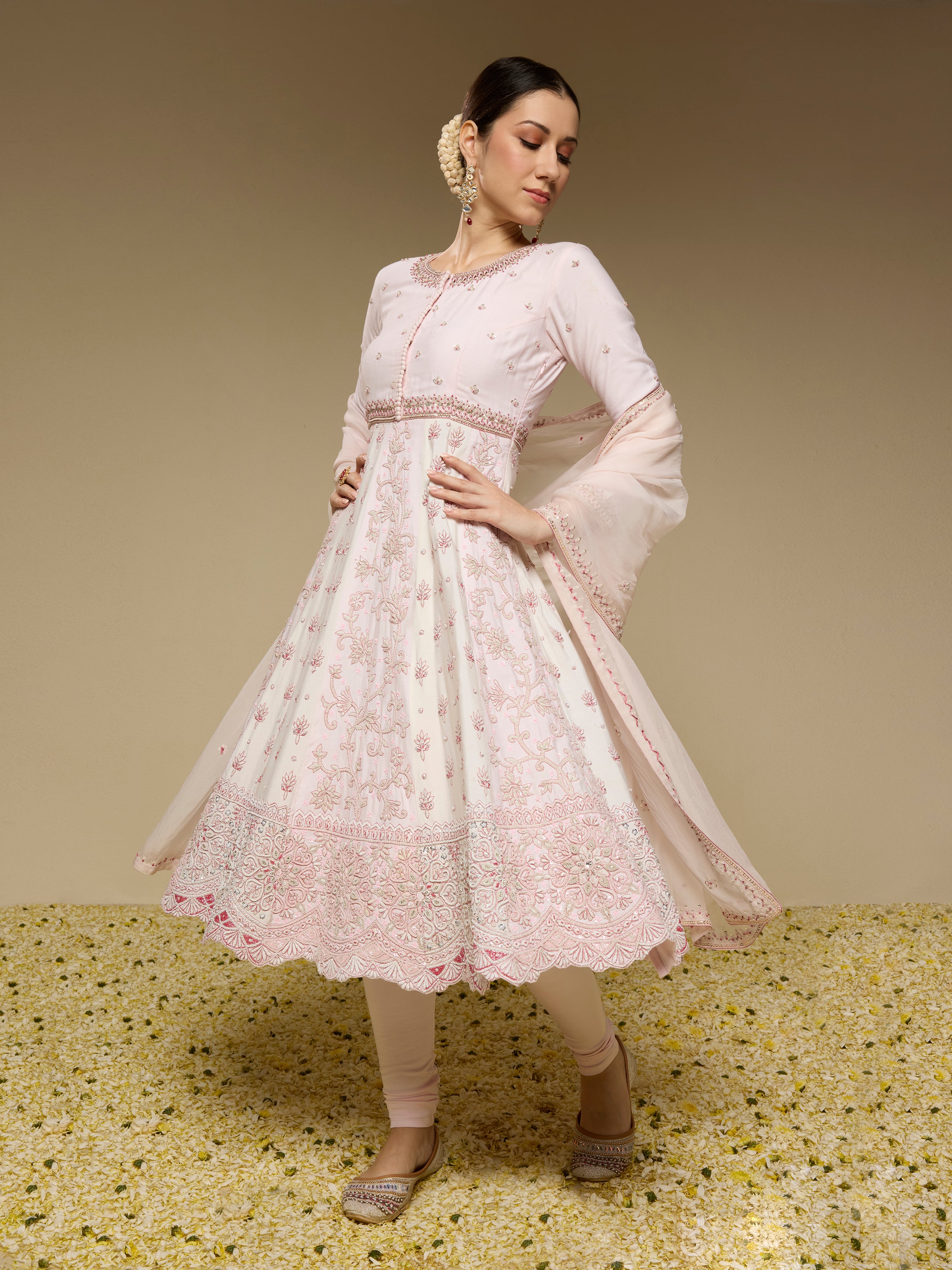 Woman wearing a light pink traditional outfit with floral patterns on a beige background