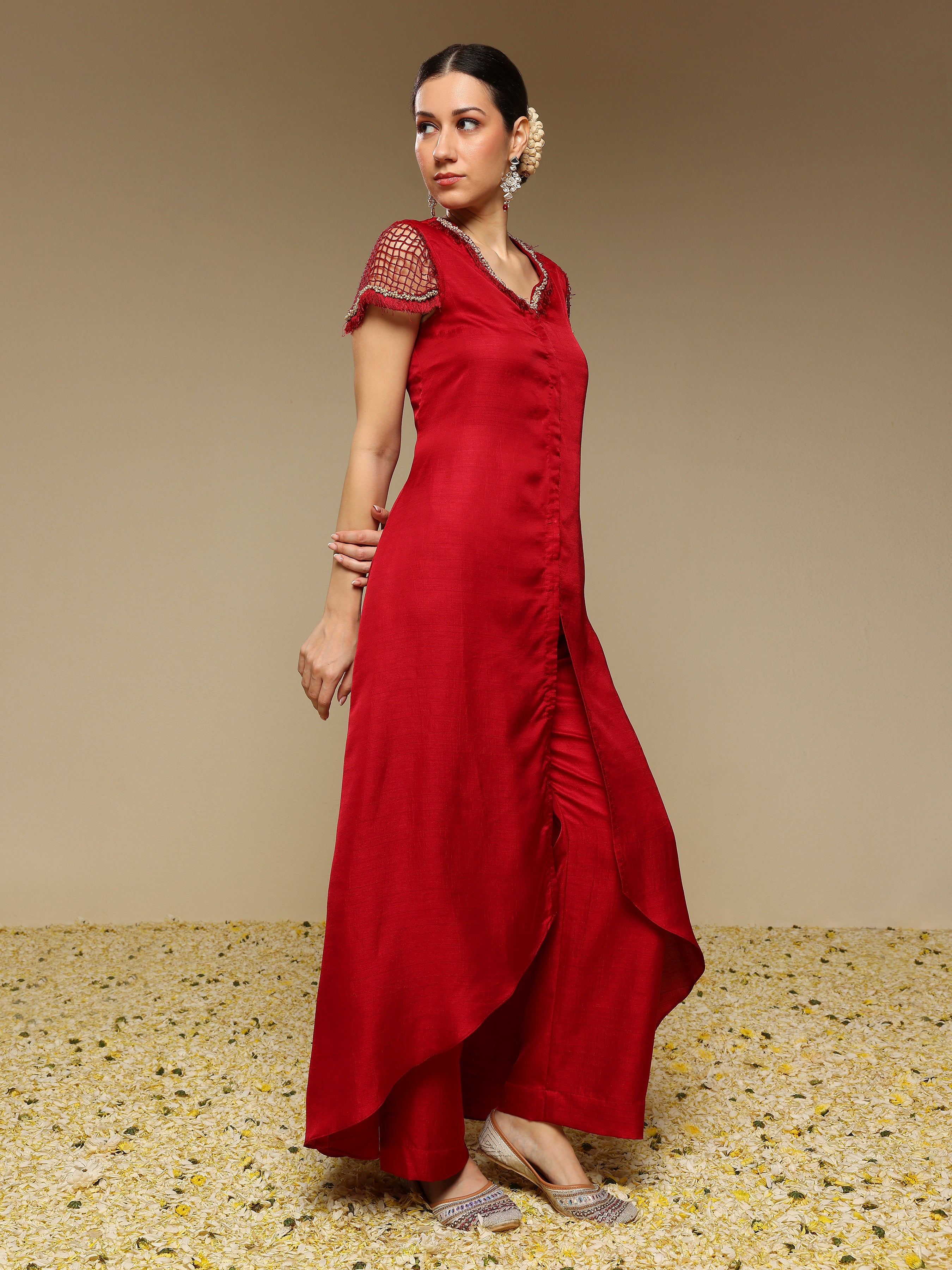 Woman wearing a red kurta set with net sleeves with a textured background