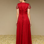 Woman wearing a red dress with floral embellishments on a beige background