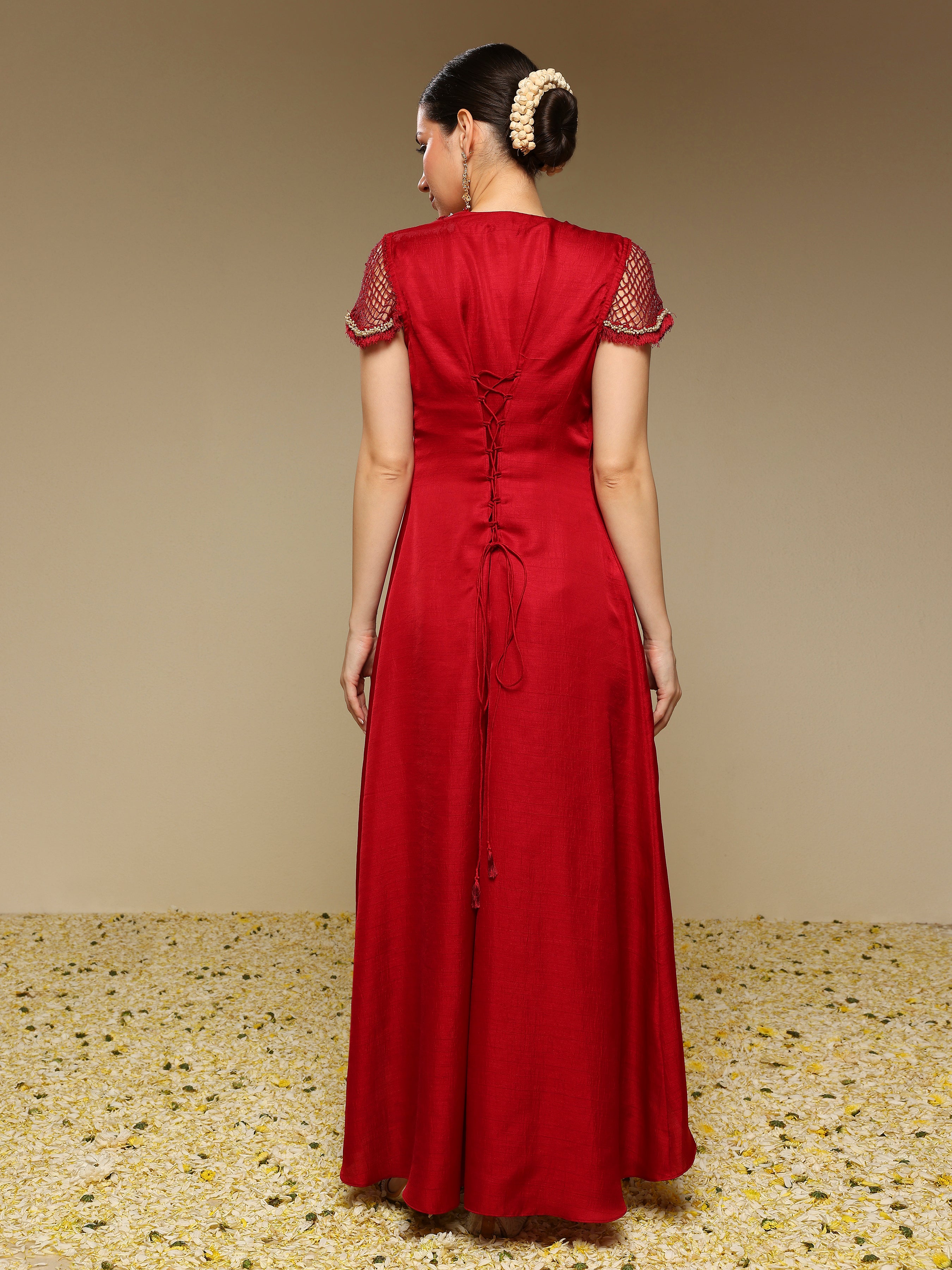 Woman wearing a red dress with floral embellishments on a beige background