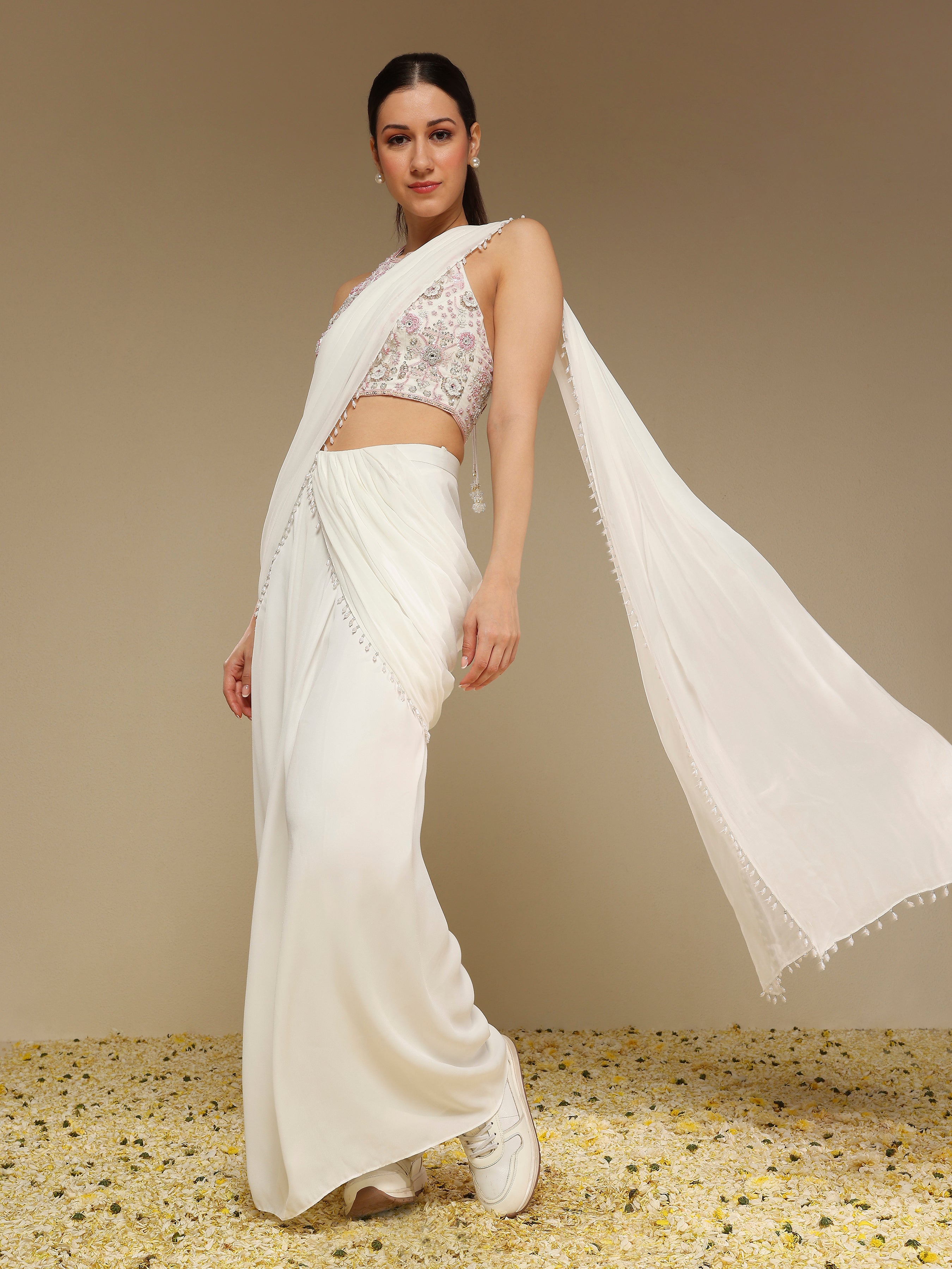 Woman wearing an ivory pre draped saree with embroidered organza blouse
