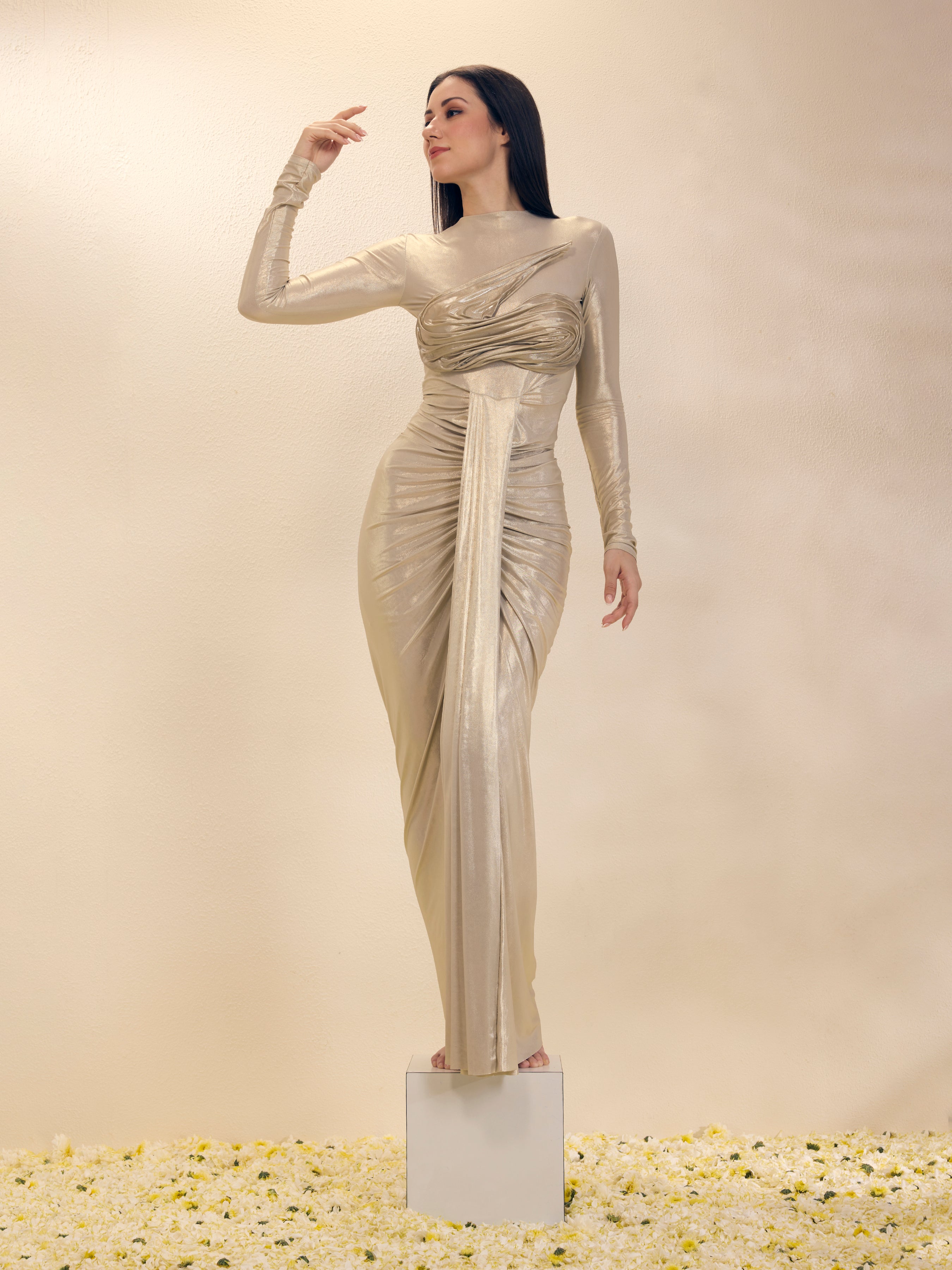 Woman in a long, elegant dress standing on a pedestal against a plain background