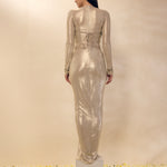 Woman wearing a long, sheer metallic dress on a beige background