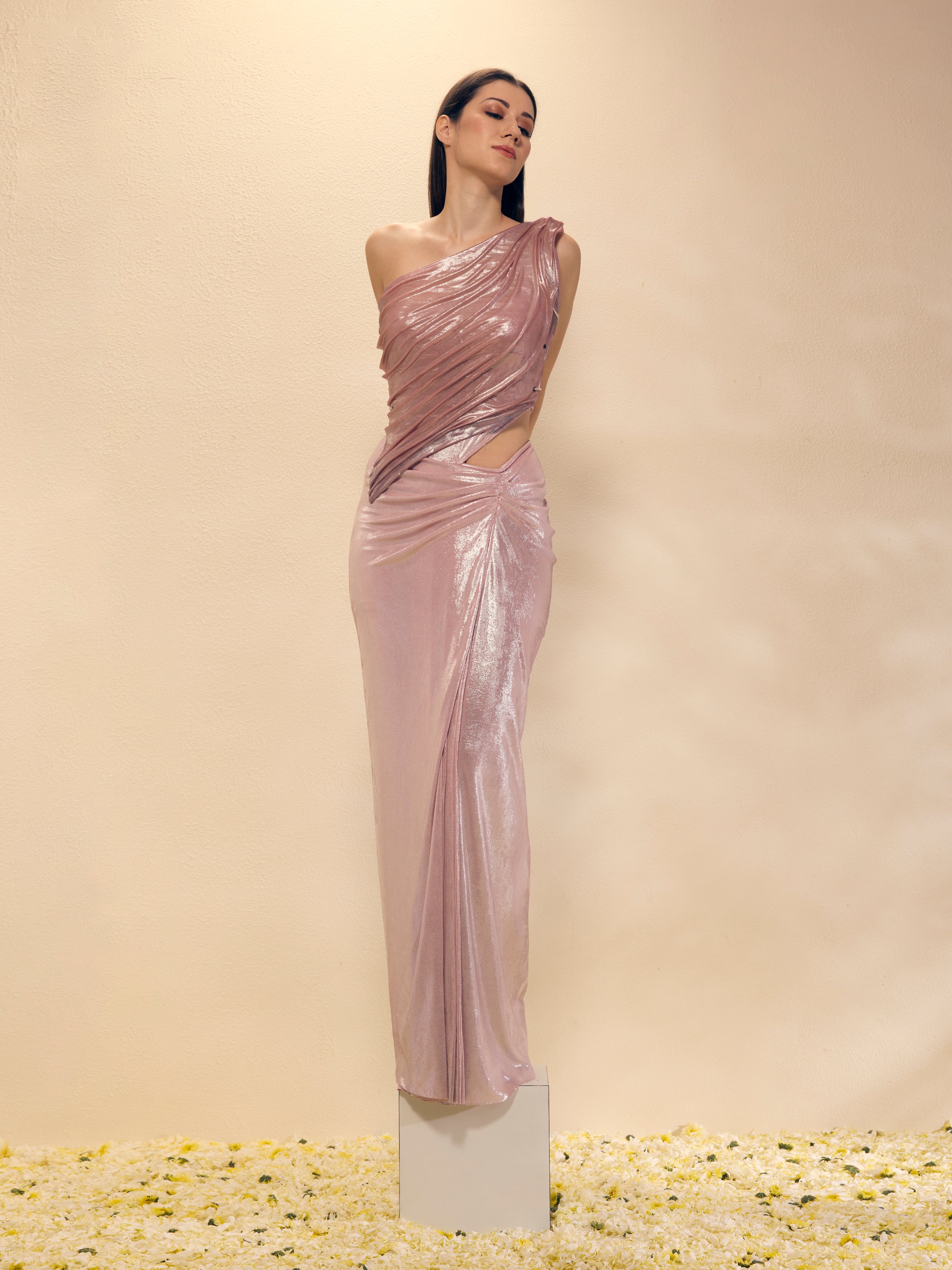 Woman wearing a one-shoulder evening gown with cut-out design on a beige background