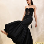 Woman wearing a black evening gown with a textured bodice on a neutral background
