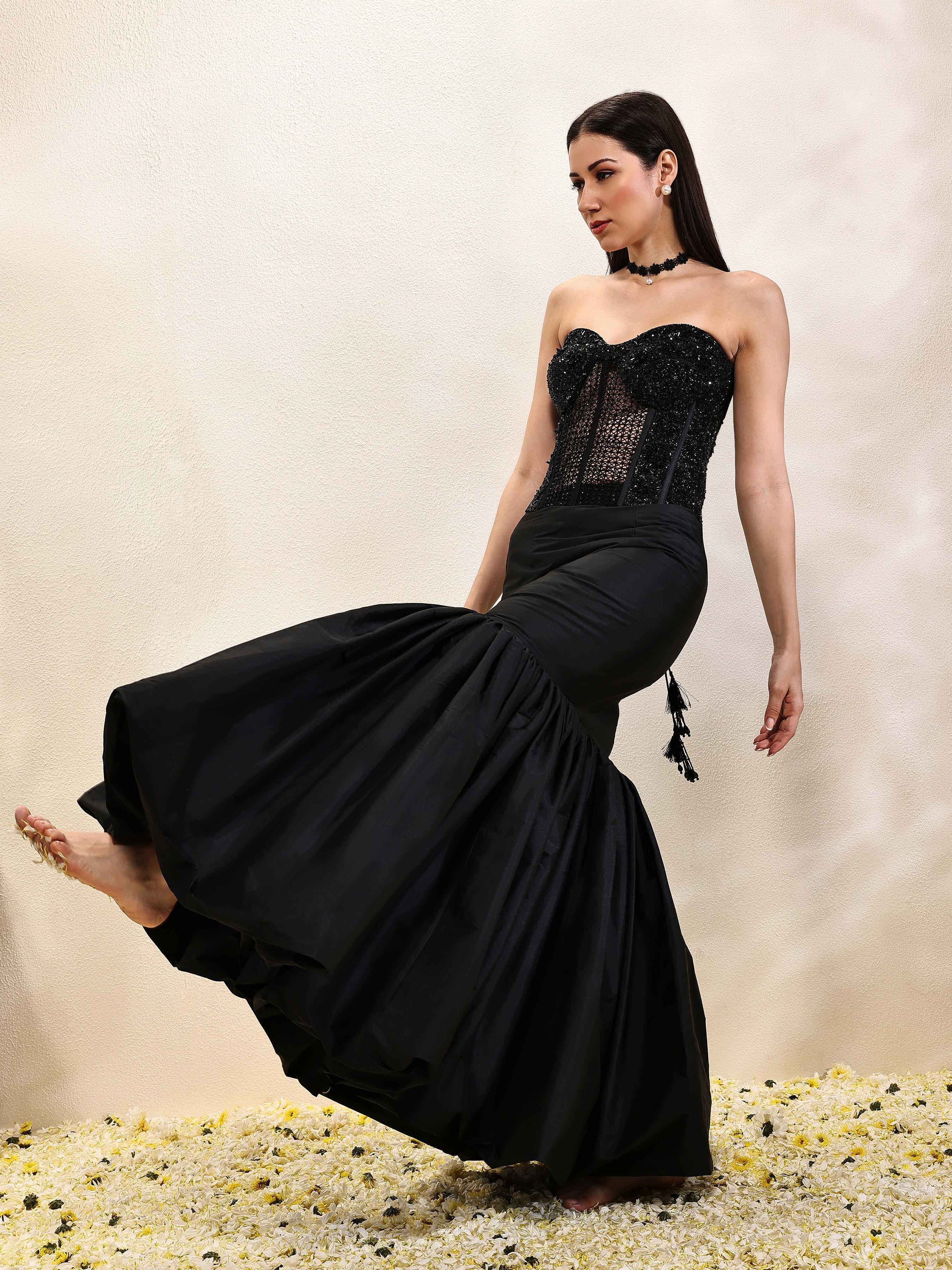 Woman wearing a black evening gown with a textured bodice on a neutral background