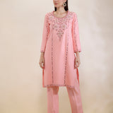Woman wearing a pink embroidered outfit on a beige background