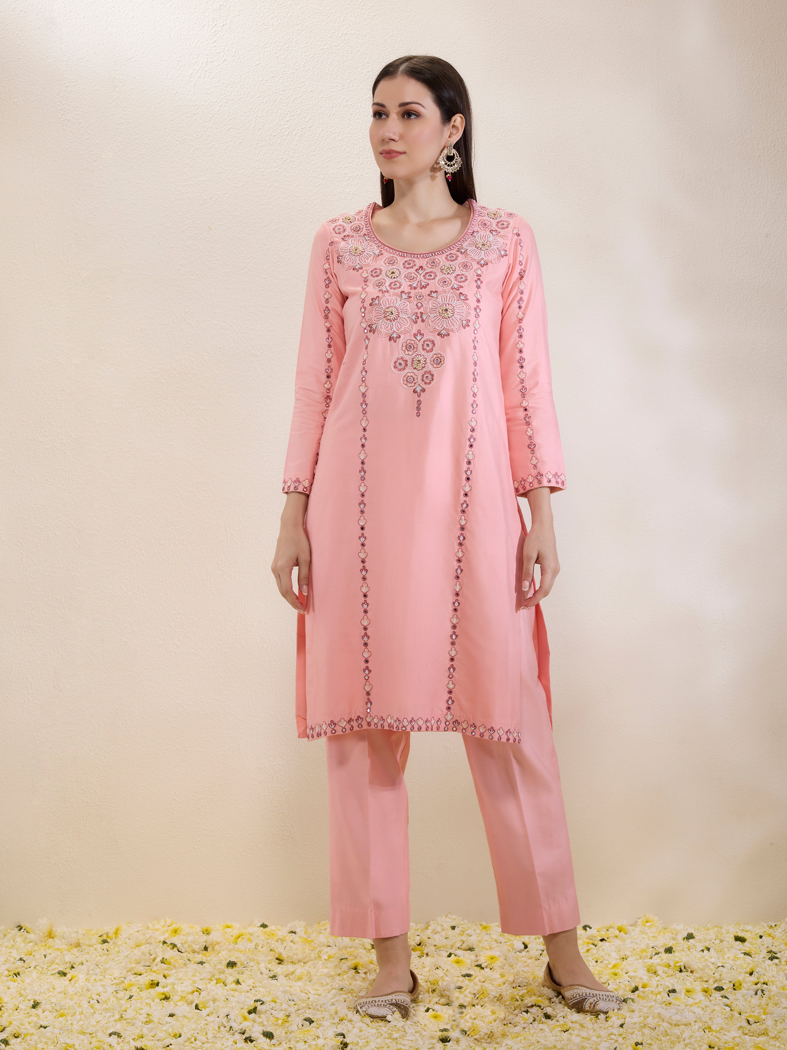 Woman wearing a pink embroidered outfit on a beige background