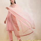 Woman wearing a pink traditional outfit with a matching dupatta on a light background
