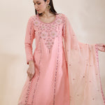 Woman wearing a pink embroidered traditional outfit with a beige background