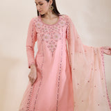 Woman wearing a pink embroidered traditional outfit with a beige background