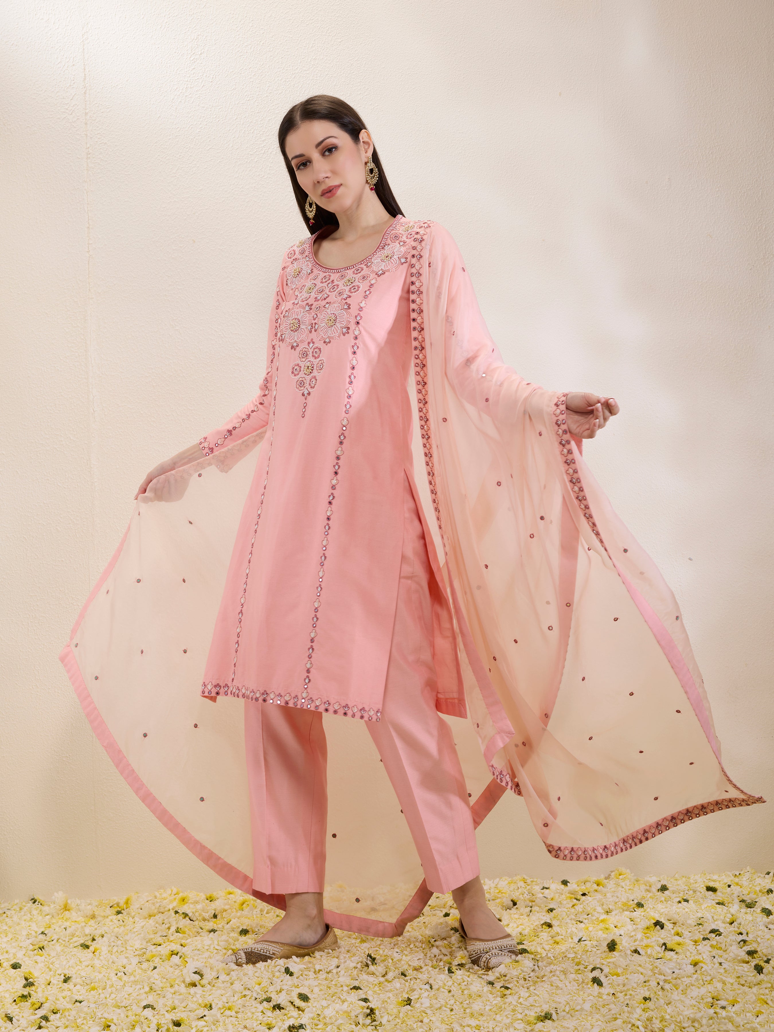 Woman wearing a pink traditional outfit with a matching dupatta on a light background