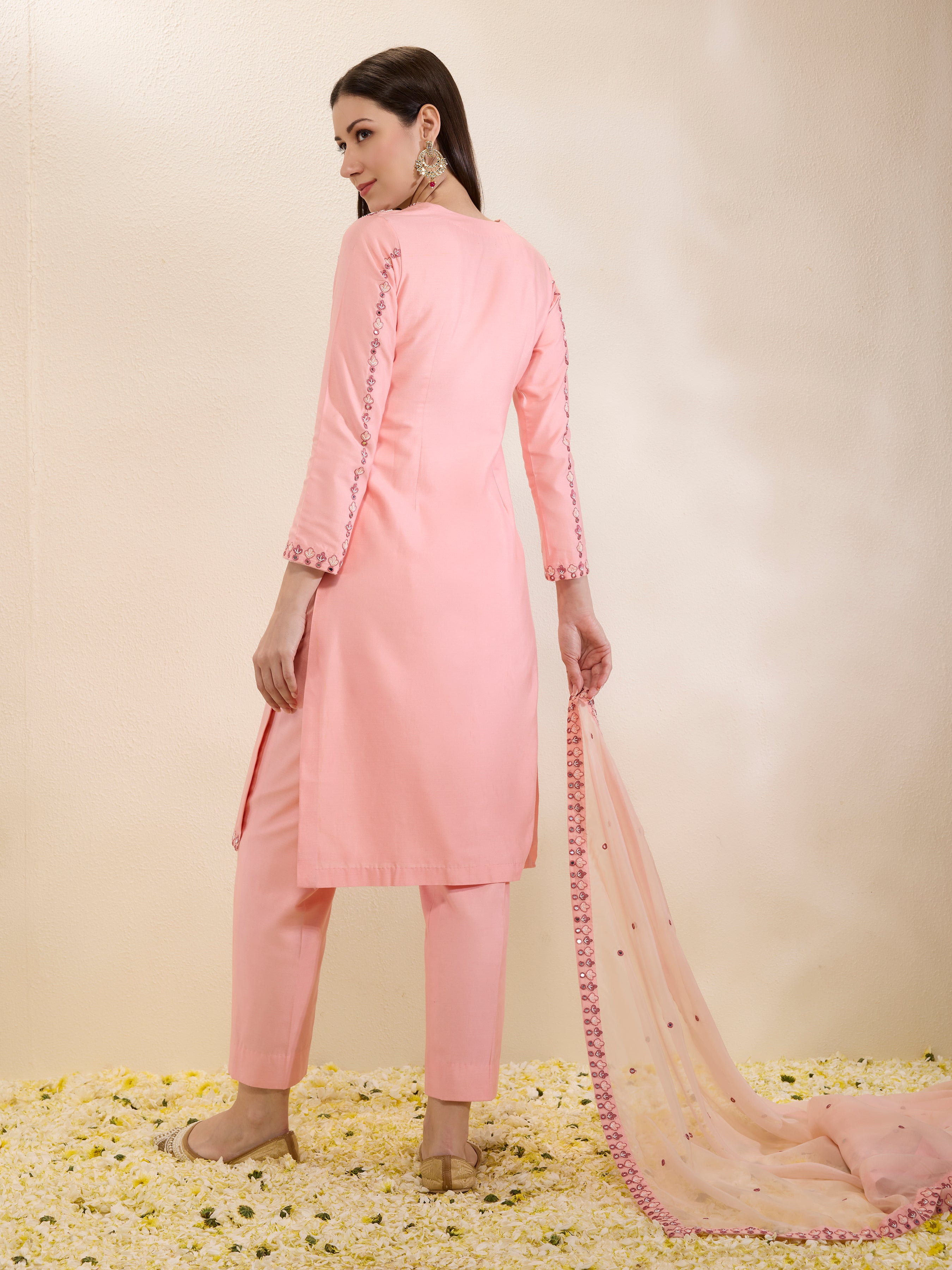 Woman wearing a pink traditional outfit with a matching dupatta on a light beige background