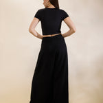 Woman wearing a black outfit with a cutout design on a beige background
