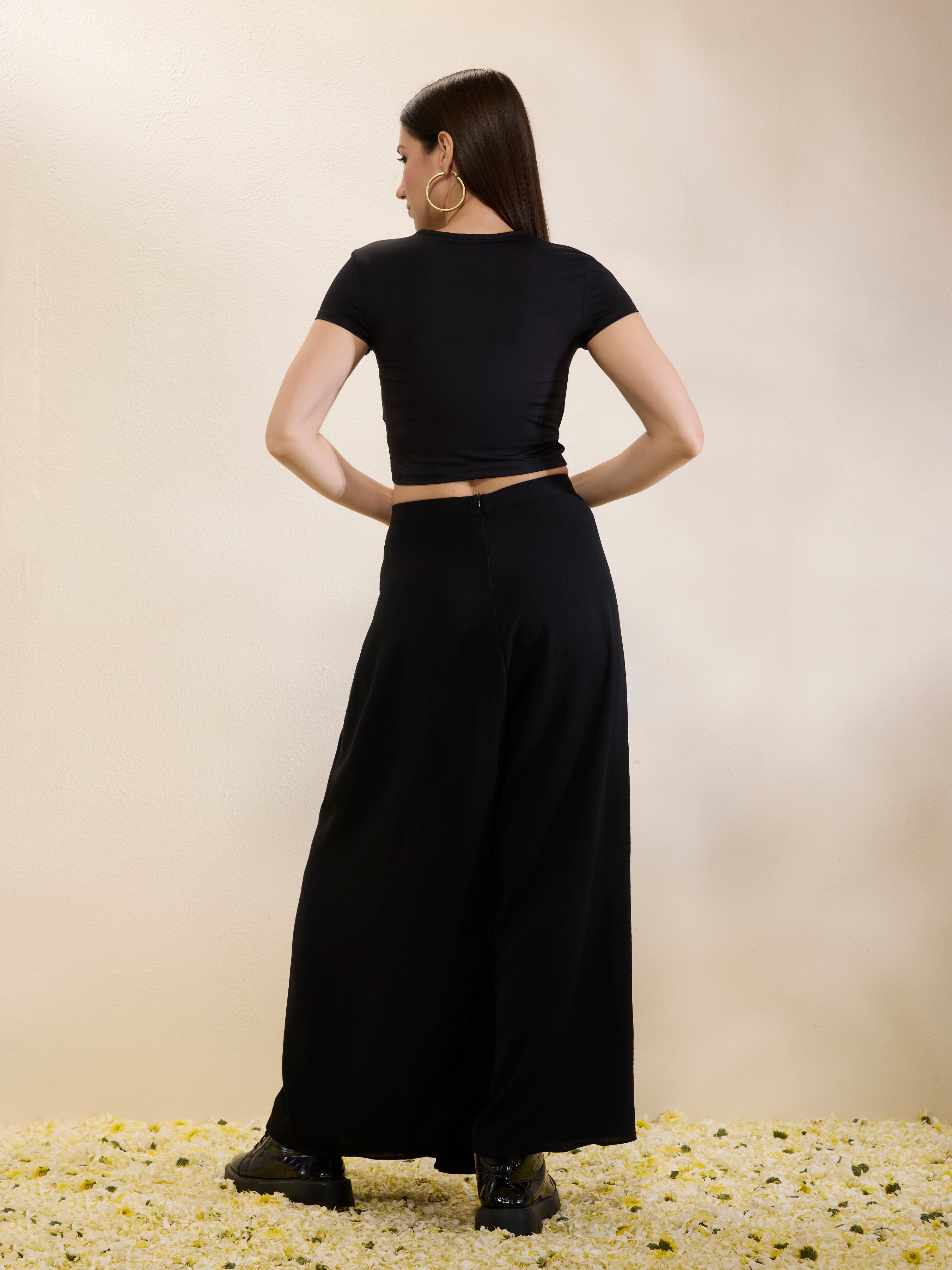 Woman wearing a black outfit with a cutout design on a beige background