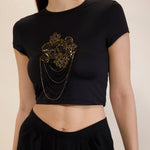 Black crop top with gold embellishments on a neutral background