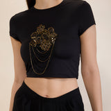 Black crop top with gold embellishments on a neutral background