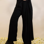 Woman wearing a mustard top and black pants on a beige background