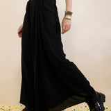 Woman wearing a mustard top and black skirt on a beige background