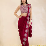 Woman wearing a maroon saree with white floral patterns on a beige background
