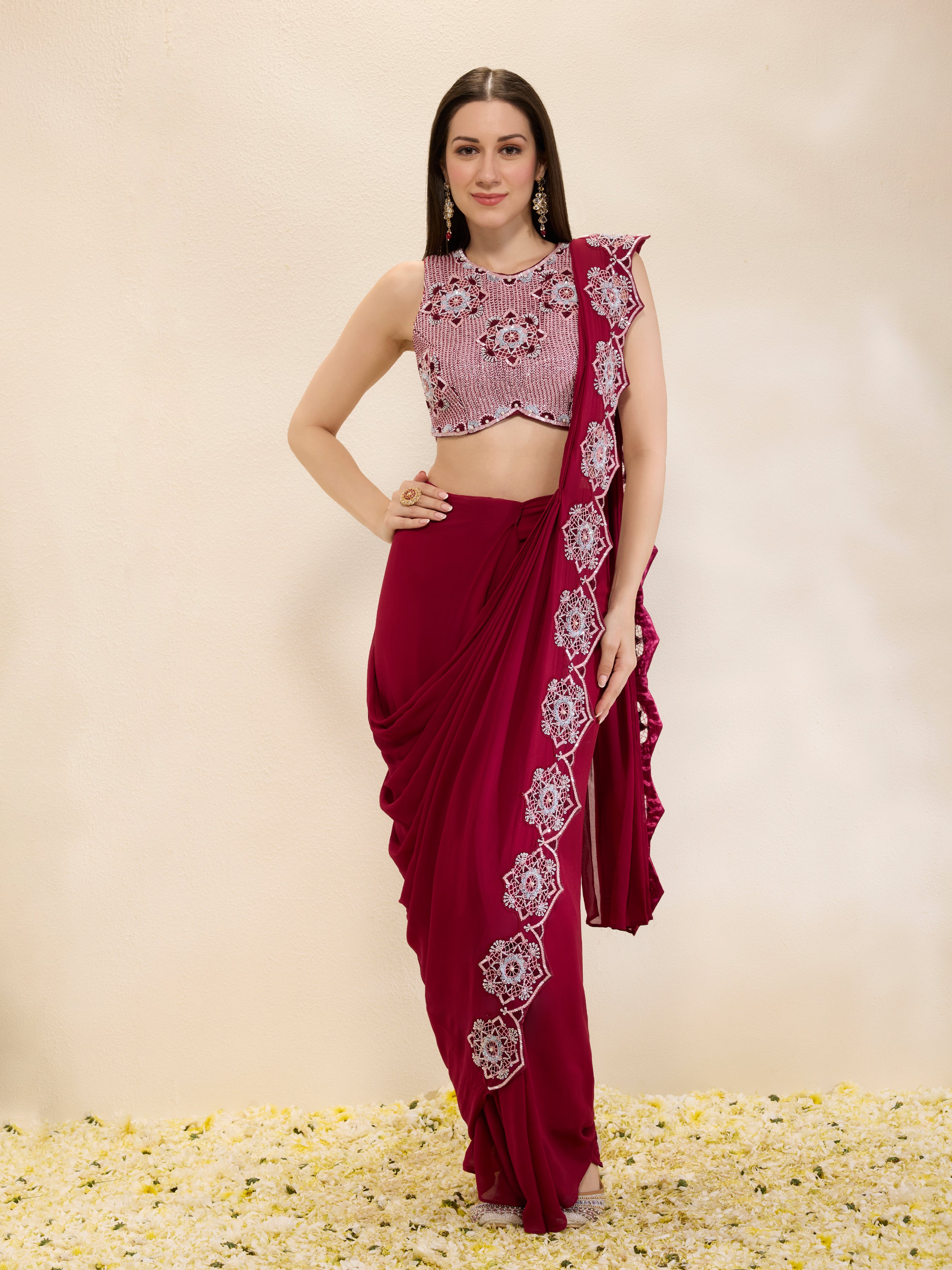 Woman wearing a maroon saree with white floral patterns on a beige background