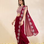 Woman wearing a maroon saree with floral patterns on a beige background