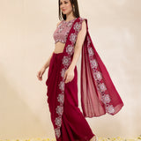 Woman wearing a maroon saree with floral patterns on a beige background