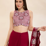 Woman wearing a pink and red traditional outfit with a matching dupatta on a beige background