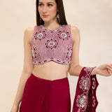Woman wearing a pink and red traditional outfit with a matching dupatta on a beige background