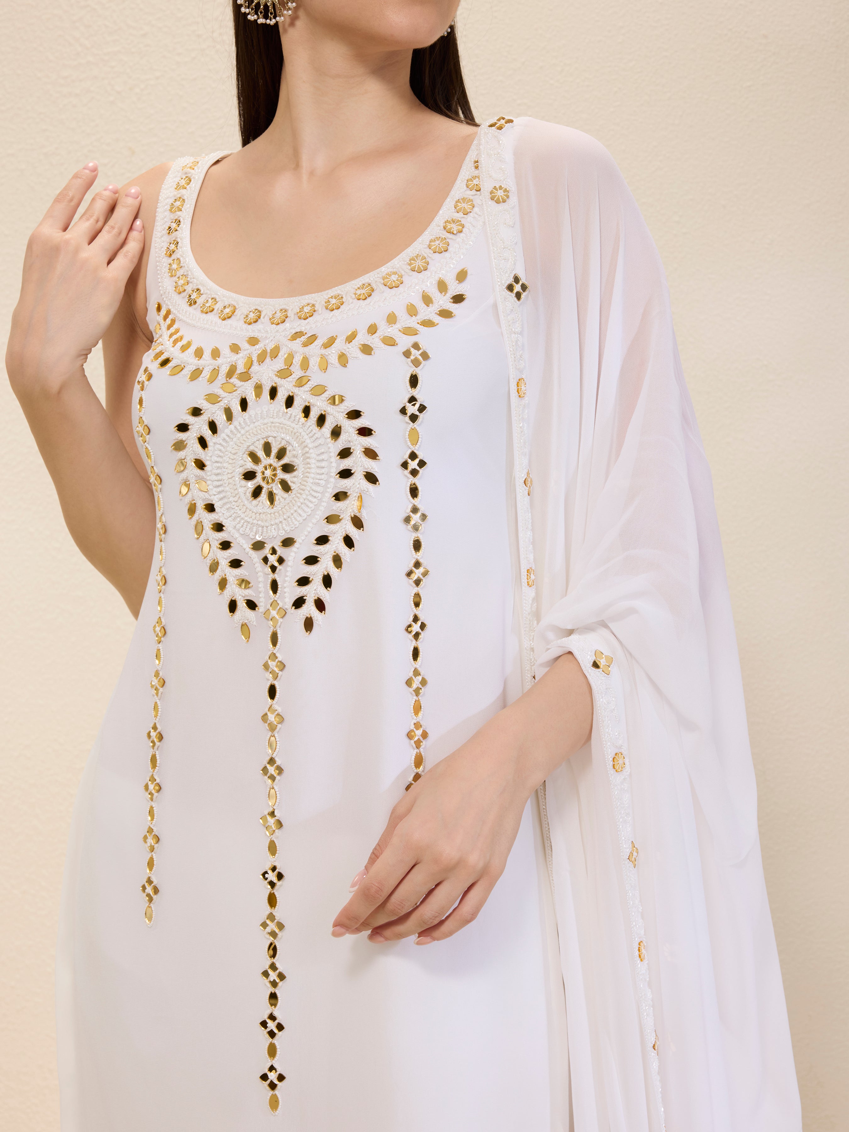 White dress with gold embroidery on a beige background
