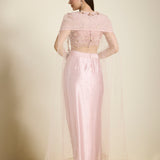 Woman wearing a light pink traditional outfit with a sheer overlay on a neutral background