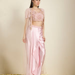 Woman wearing a pink traditional outfit with a top and pants on a beige background