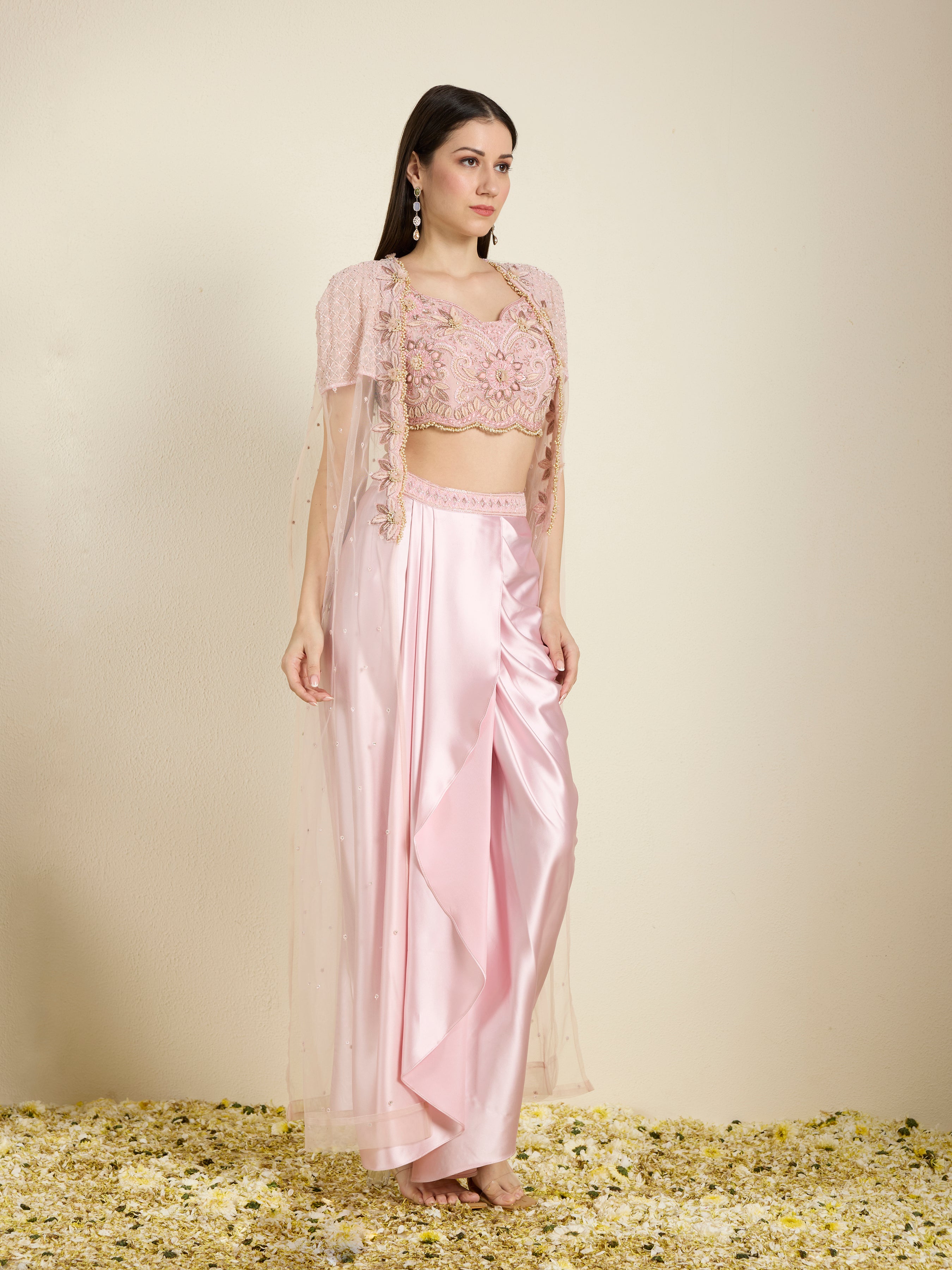 Woman wearing a pink traditional outfit with a top and pants on a beige background