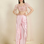 Woman wearing a pink saree with a matching blouse against a neutral background