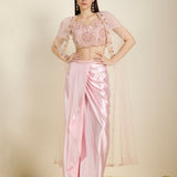 Woman wearing a pink saree with a matching blouse against a neutral background