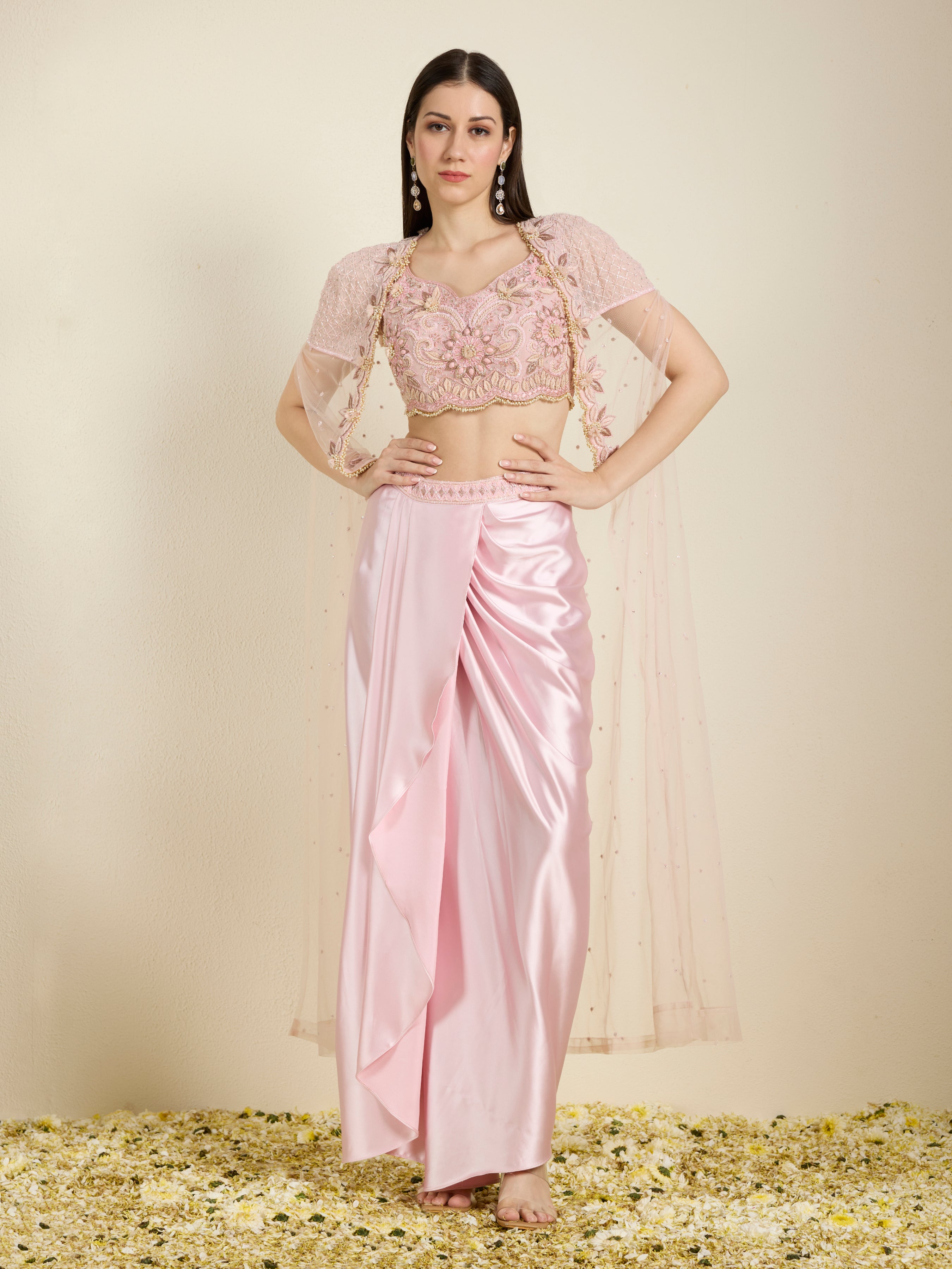 Woman wearing a pink saree with a matching blouse against a neutral background
